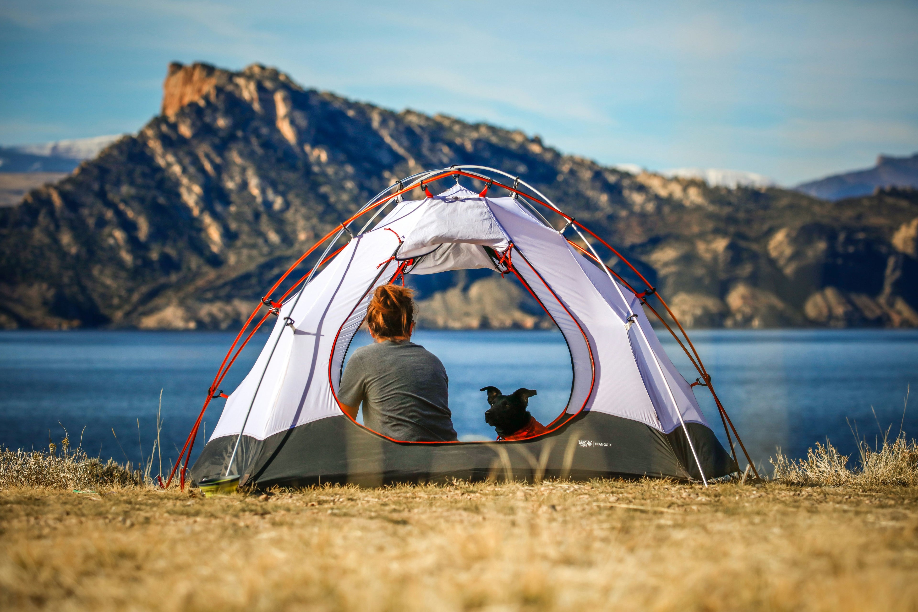 Woman and her dog in a tent by a lake